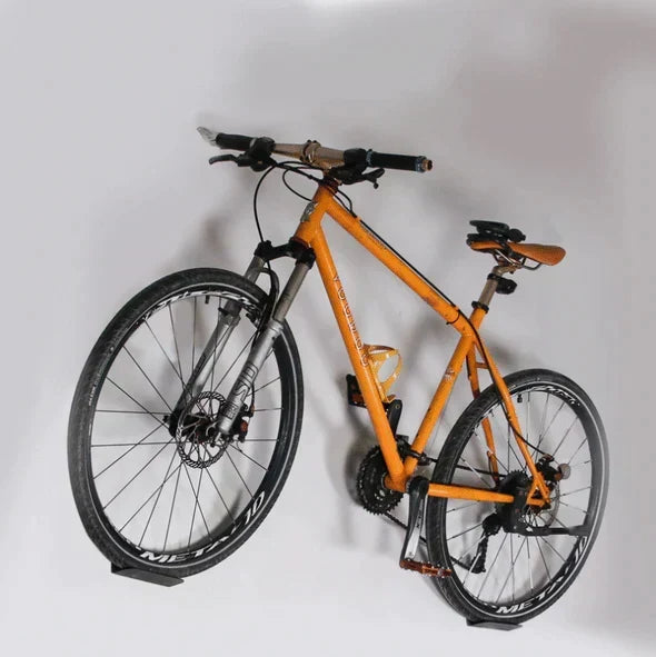 Oranje mountainbike stevig gemonteerd aan de wand met de fietshaak