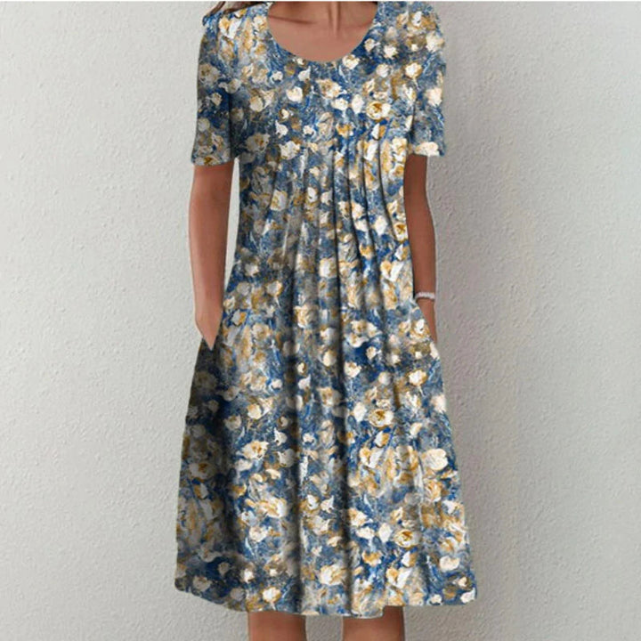 Model draagt casual dames midi zomerjurk met fleurige bloemenprint, v-hals en zakken. Luchtig en elegant.