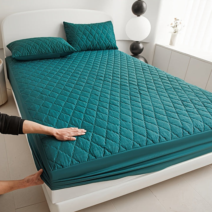 Groene gewatteerde waterdichte matrasbeschermer op een opgemaakt bed