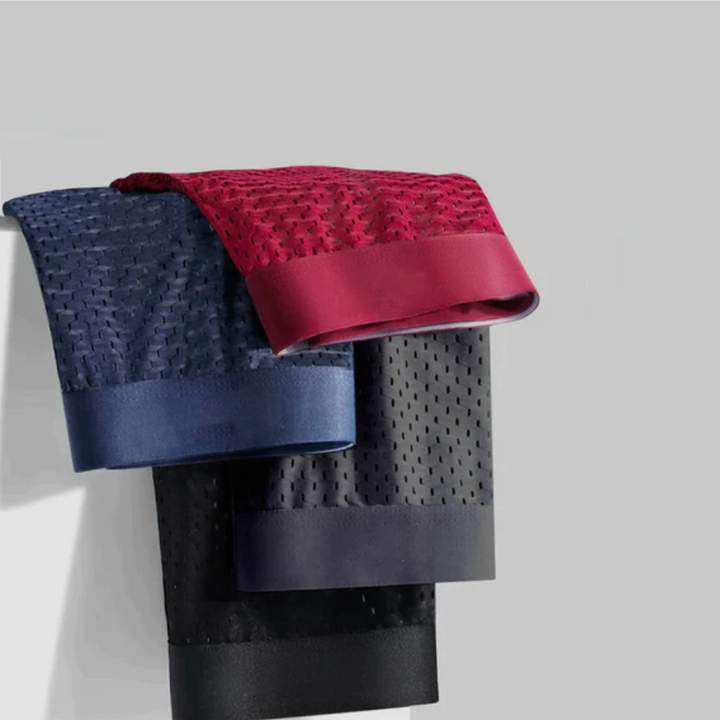 Drie kleurrijke heren boxershorts in blauw, rood en zwart, netjes opgevouwen en gestapeld.