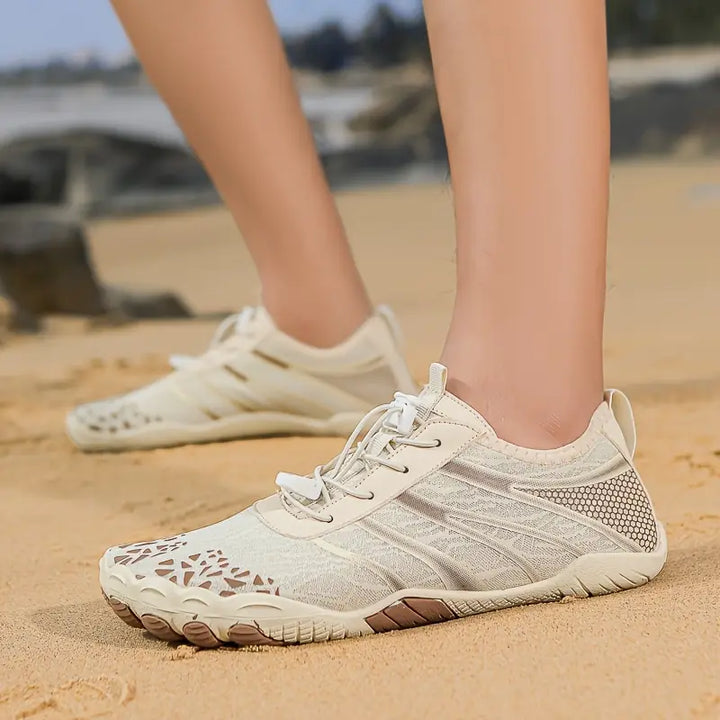 Heren waterschoenen in beige, gedragen op een zandstrand, comfortabel en lichtgewicht.