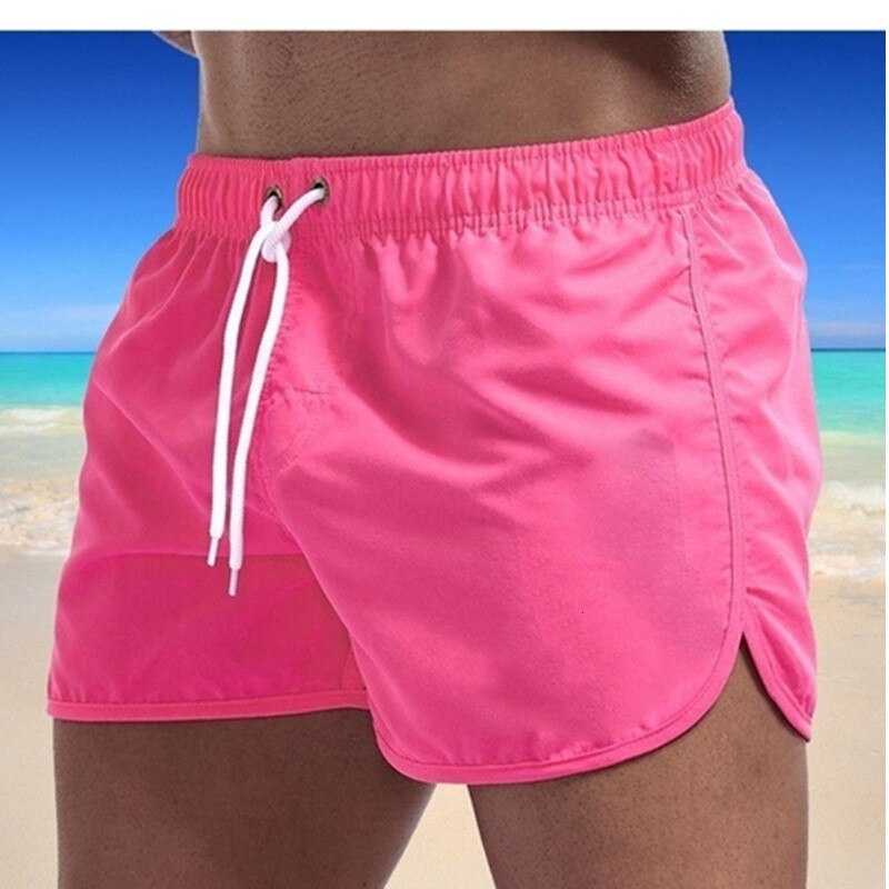 Man draagt een Heren Ryan zwemshort aan een zonnig strand. Stijlvolle en comfortabele zomerkleding voor heren.