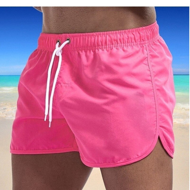 Man draagt een Heren Ryan zwemshort aan een zonnig strand. Stijlvolle en comfortabele zomerkleding voor heren.