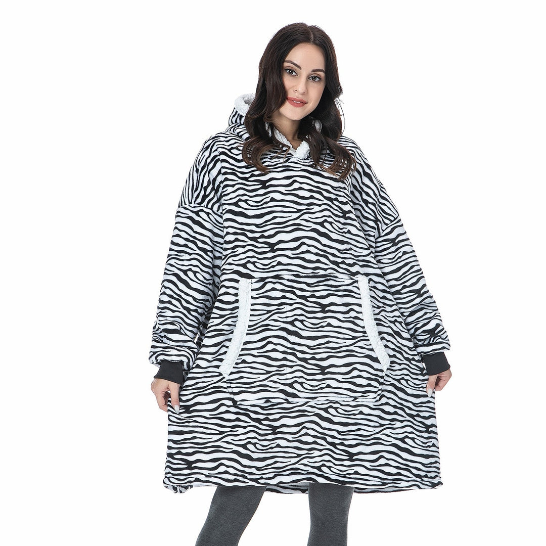 Man geniet van de warme, oversized dekenhoodie op de bank. Ultiem comfort.