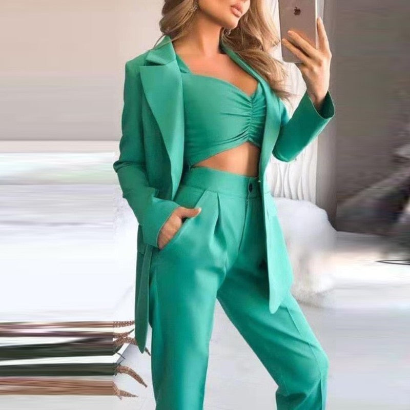 Vrouw draagt een groene driedelige dames blazer set met broek en top