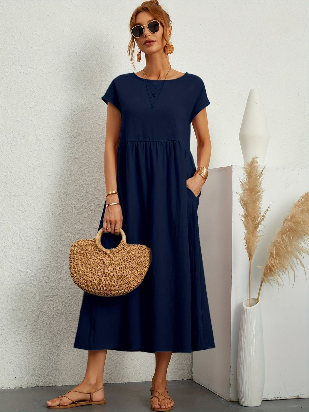 Model draagt een marineblauwe lichte midijurk met handtas