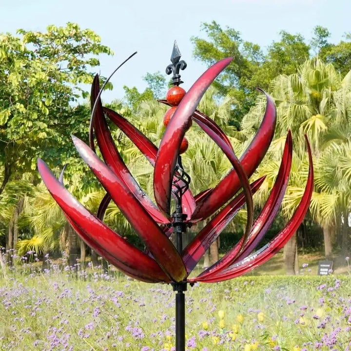 Artistieke metalen windspinner, blauw en rood. Sierlijke tuindecoratie die draait en rust brengt in de buitenruimte.