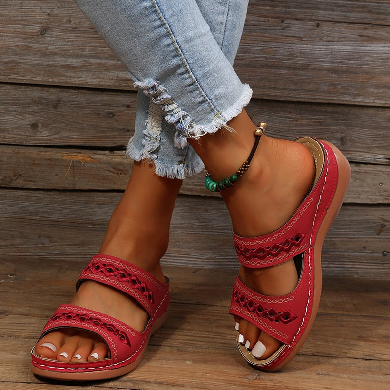 Stijlvolle rode orthopedische sandalen voor dames, gedragen, toont elegant ontwerp en ondersteuning.