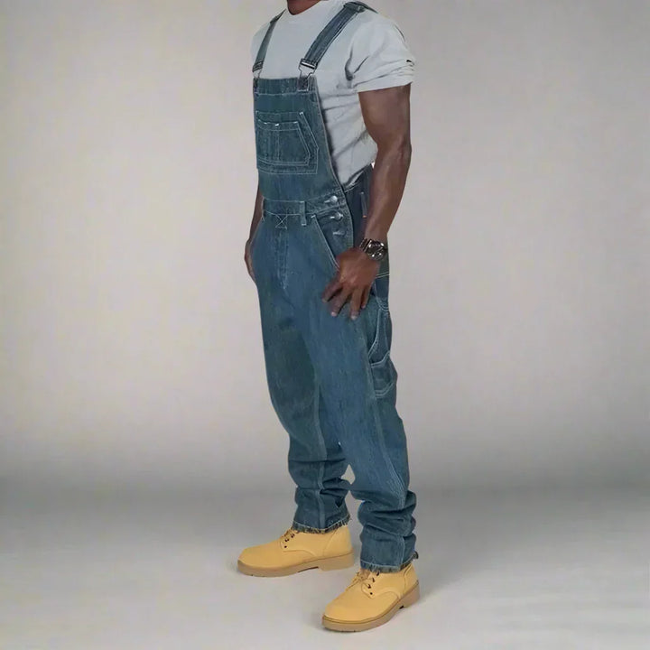 Donkerblauwe heren denim overall met rechte pijpen. Comfortabele spijkeroverall voor moderne werkkledingstijl.