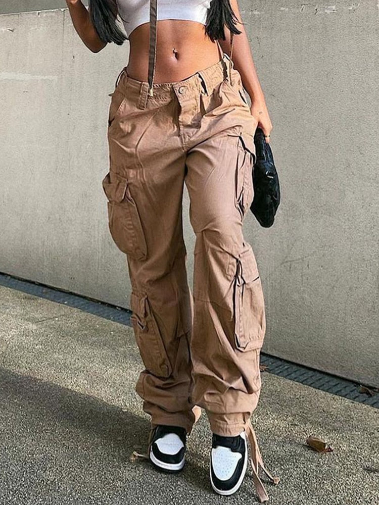 Zijaanzicht van een vrouw in een khaki cargobroek met wijde pijpen en witte crop top, met handtas.