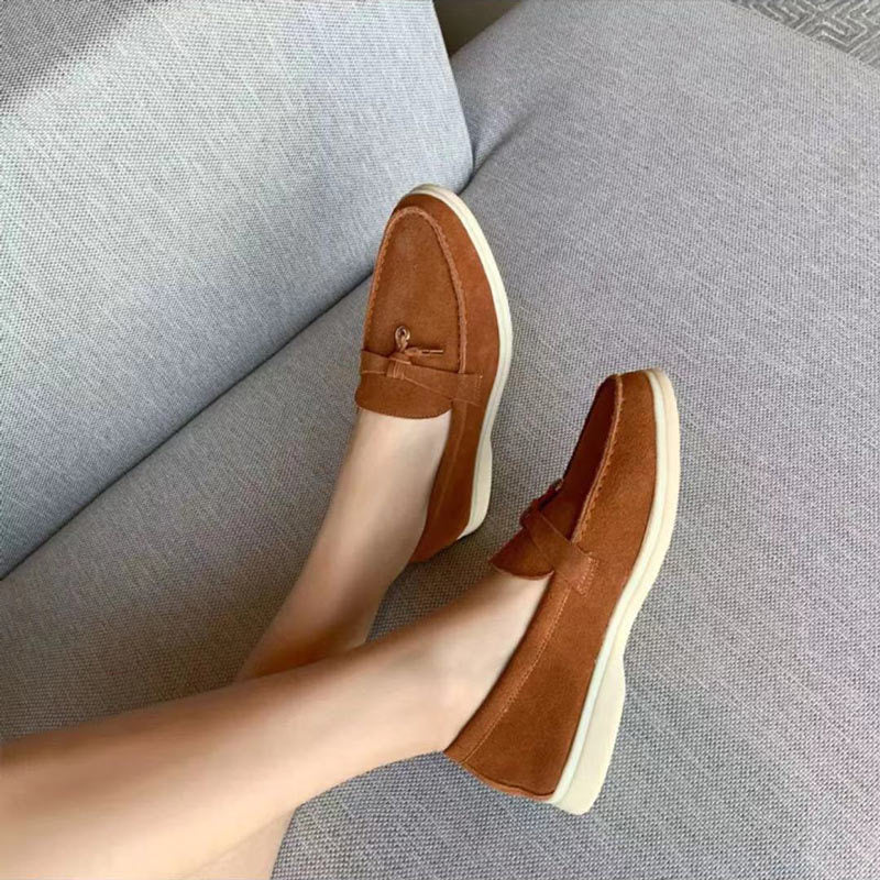 Bruine suède loafers voor dames met comfortabele zool op een grijze bank