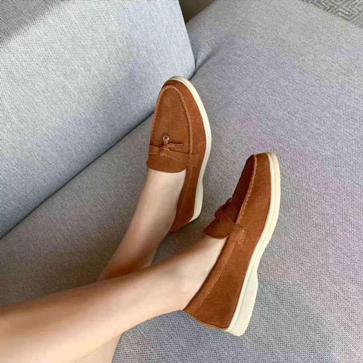 Bruine suède loafers voor dames met comfortabele zool op een grijze bank
