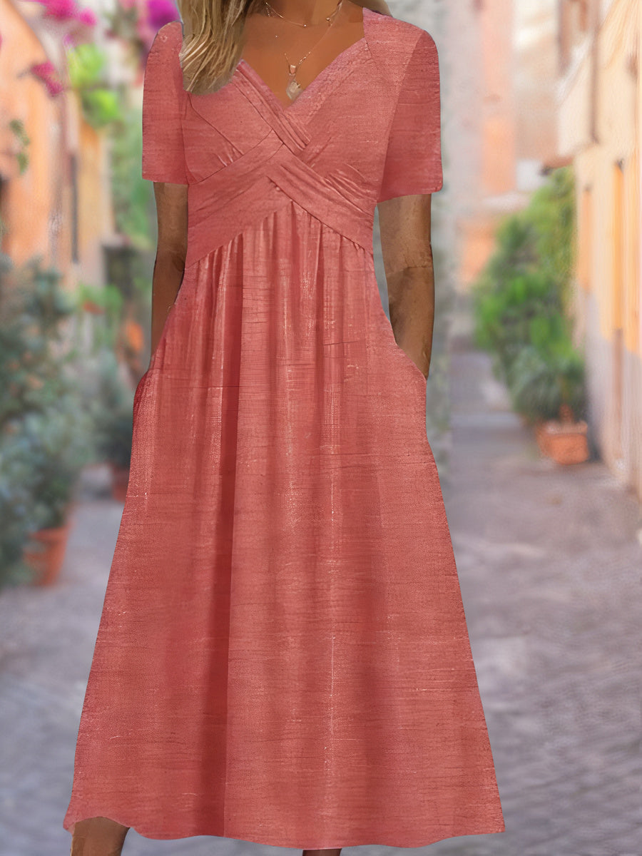 Model draagt een lichte zomerjurk met geplooide taille en v-hals, staand in een steegje