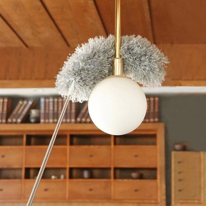 Persoon reinigt hoge lamp met uitschuifbare stofverwijderaar, bereik tot 5 meter. Efficiënt huishouden.