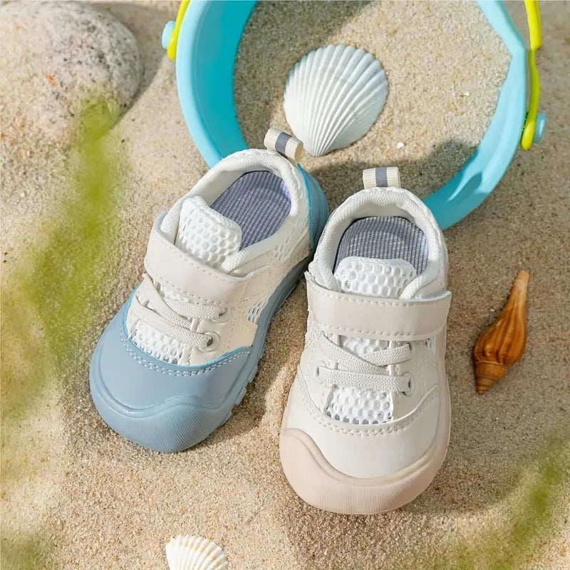 Lachende baby draagt flexibele blauwe barefoot babyschoenen, genietend van natuurlijke voetontwikkeling.