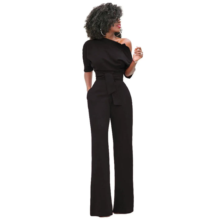 Avondkleding jumpsuit: damesmodel met open schouder, strikdetail en wijde broekspijpen.