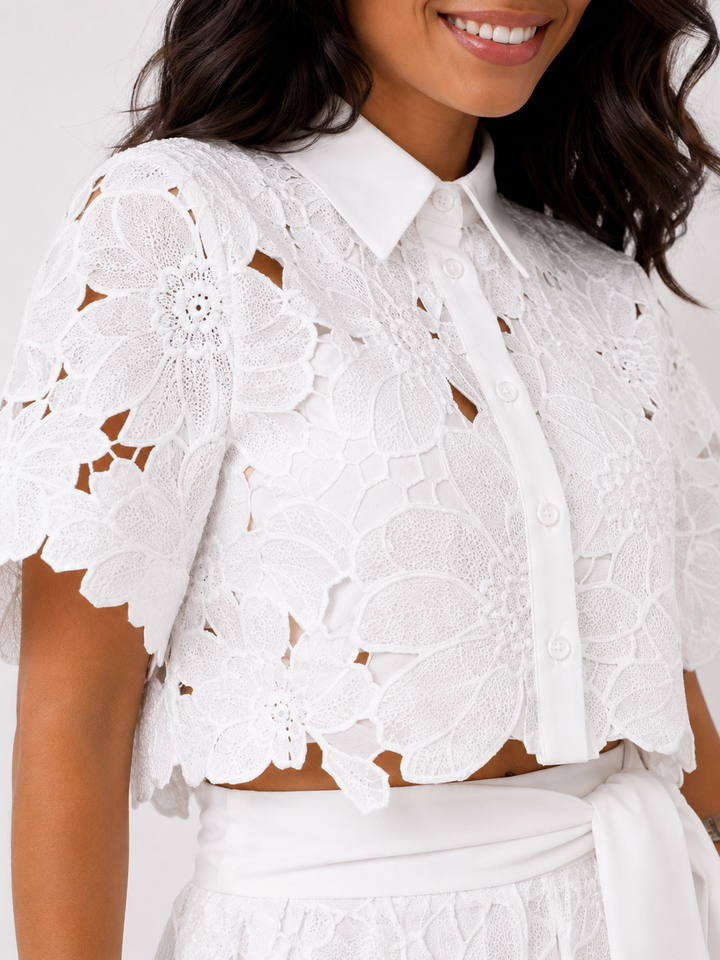 Close-up van de witte kanten crop top met kraag en knoopsluiting.