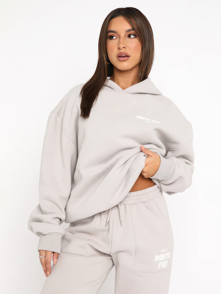 "Dames trainingspak met oversized pasvorm, wit, elastische ribboorden, trendy puffprint logo en fleecestof."