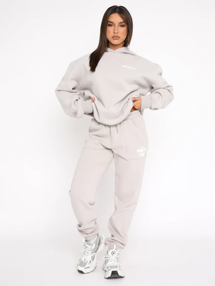 "Dames trainingspak met oversized pasvorm, wit, elastische ribboorden, trendy puffprint logo en fleecestof."