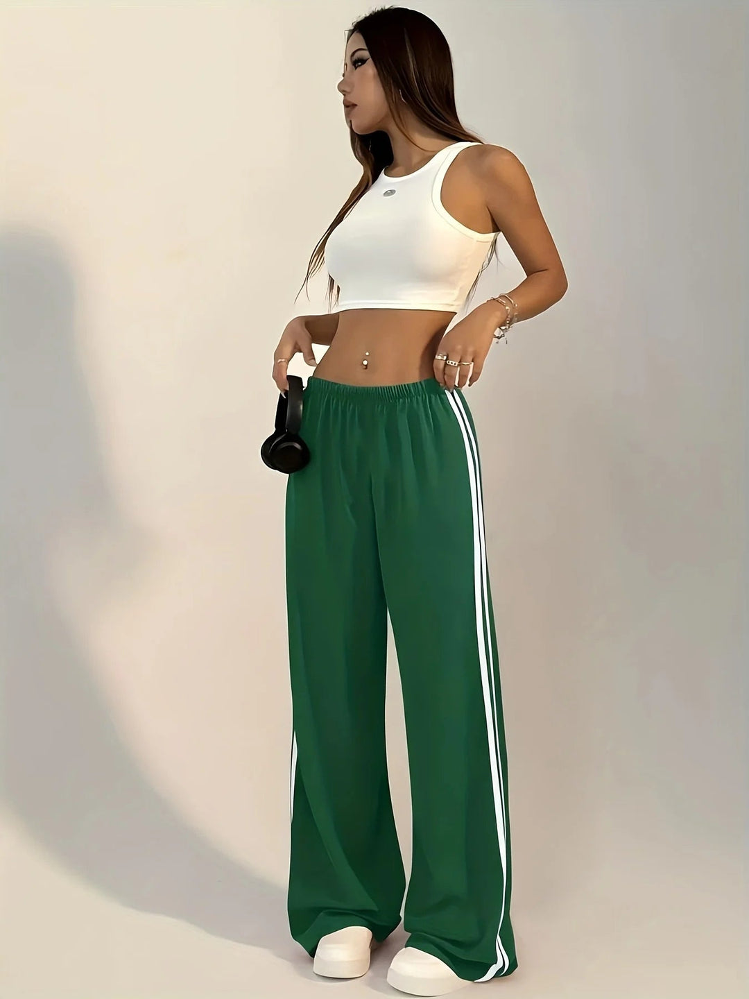Vrouw draagt groene trainingsbroek met wijde pijpen en witte zijstreep