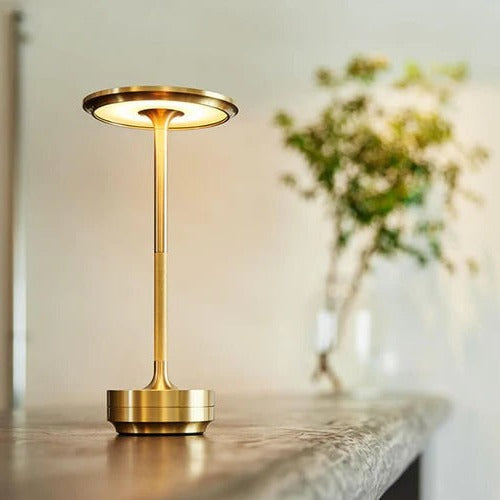 Gouden draadloze tafellamp op een tafel, verlicht een ruimte met warm licht