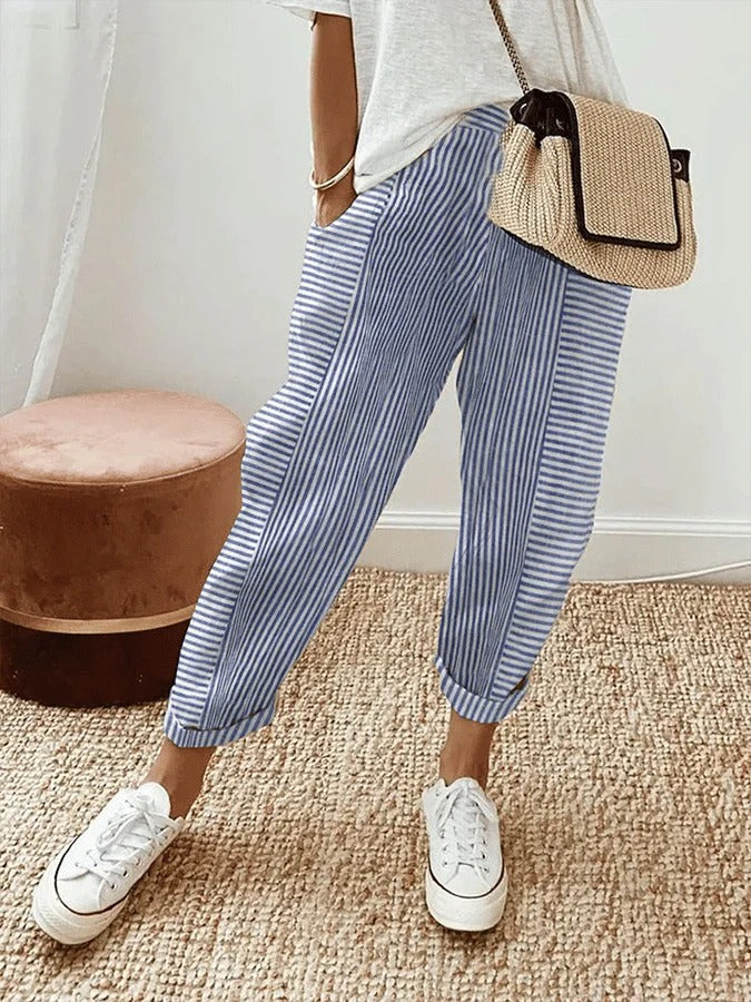 Vrouw draagt blauw gestreepte dames zomerbroek met hoge taille en sneakers