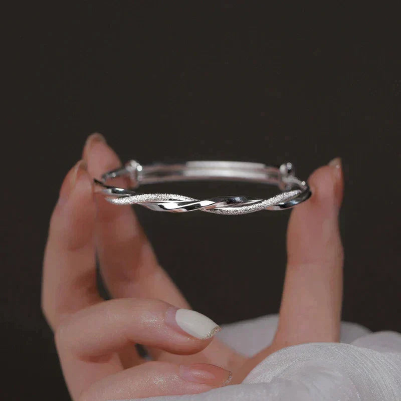 "Elegant gedraaide zilveren armband, verstelbaar, met gedetailleerd ontwerp. Perfect voor elke gelegenheid."