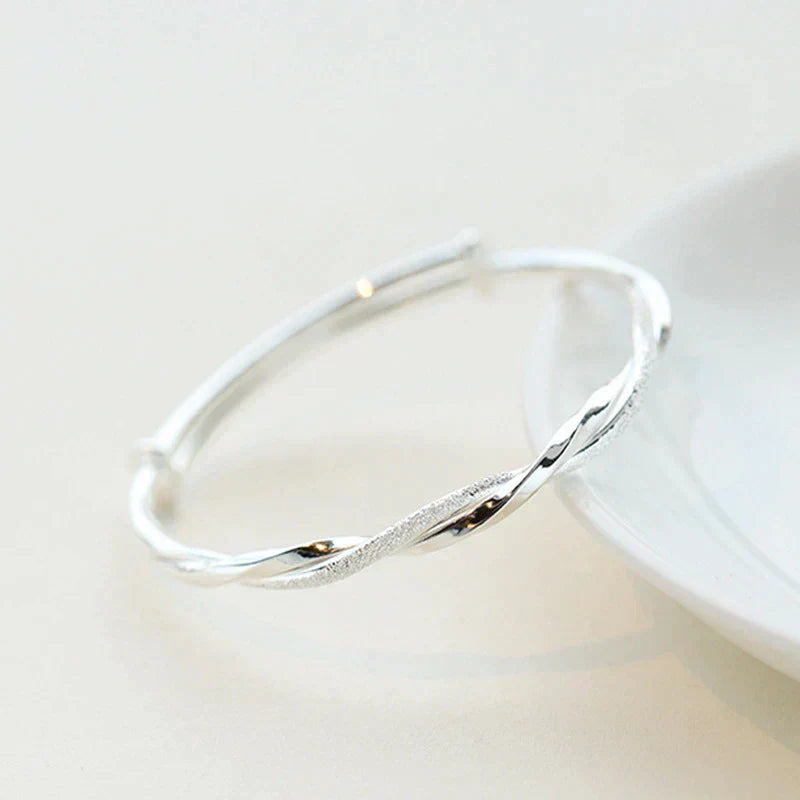 "Elegant gedraaide zilveren armband, verstelbaar, met gedetailleerd ontwerp. Perfect voor elke gelegenheid."