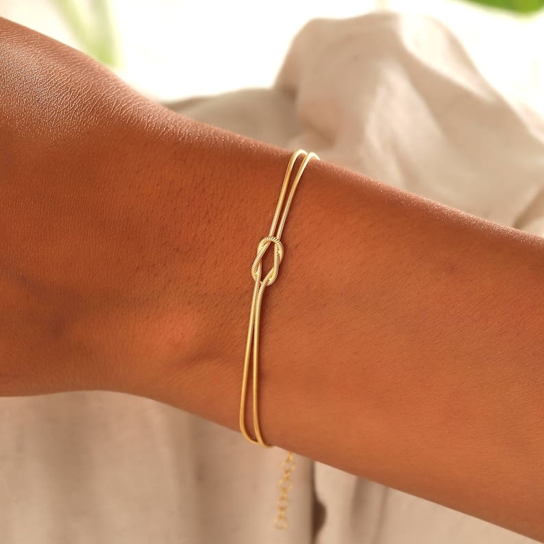 "Elegant gouden liefdesknoop armband voor dames, minimalistisch ontwerp, tijdloos en verfijnd accessoire."