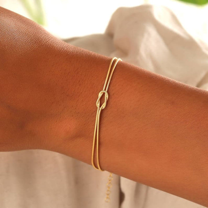 "Elegant gouden liefdesknoop armband voor dames, minimalistisch ontwerp, tijdloos en verfijnd accessoire."