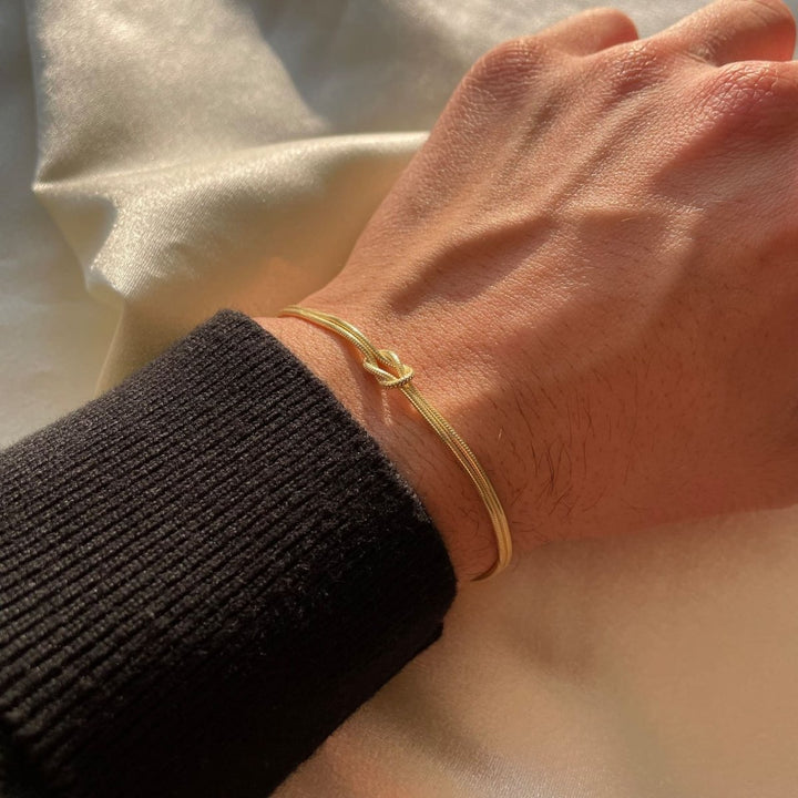"Elegant gouden liefdesknoop armband voor dames, minimalistisch ontwerp, tijdloos en verfijnd accessoire."
