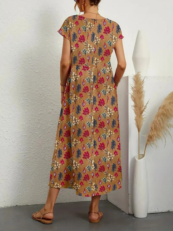 "Elegante A-lijn zomerjurk met kleurrijke bloemenprint, korte mouwen en lange rok, gemaakt van licht katoenen stof."