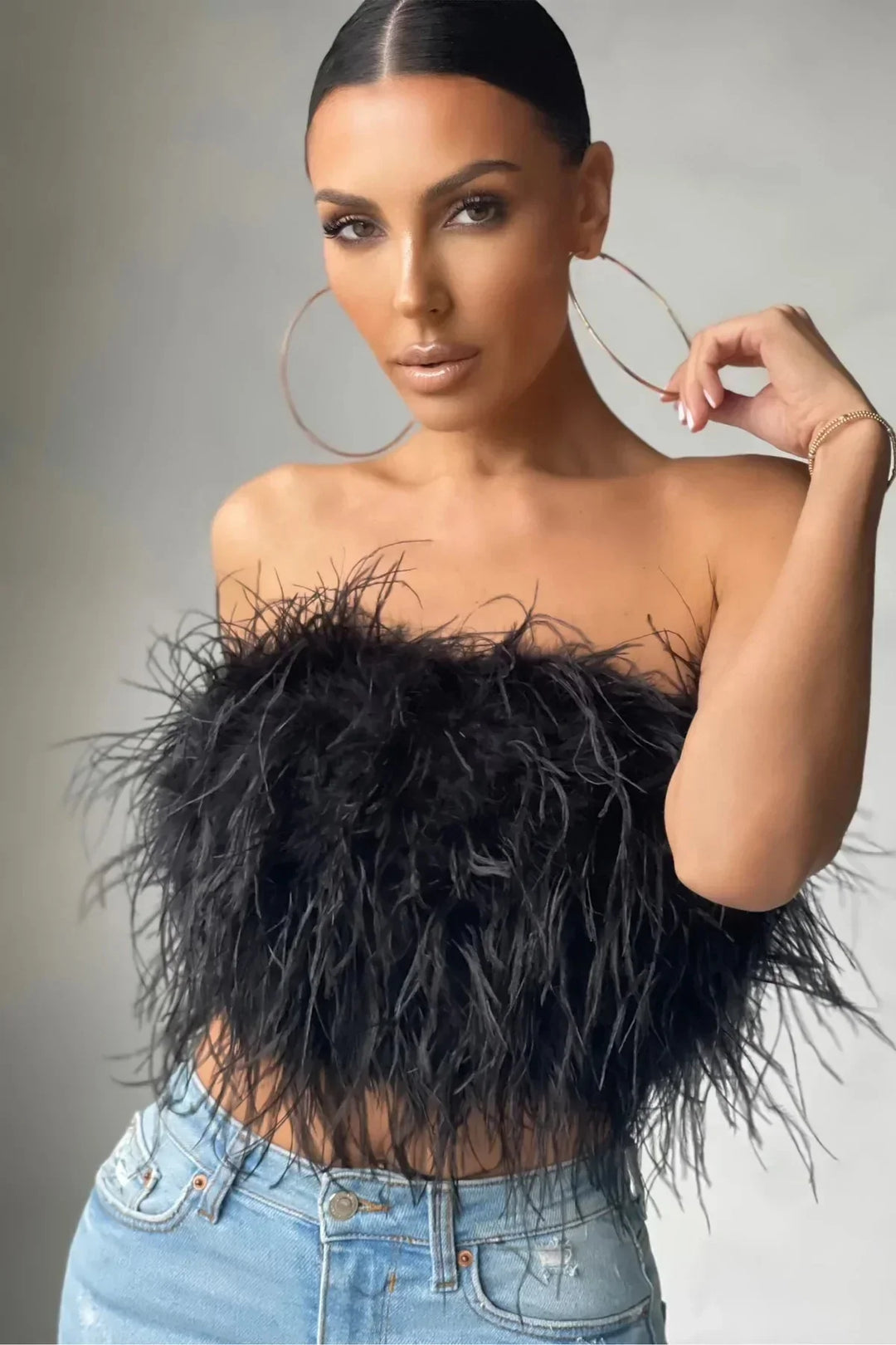 Modebewuste mouwloze crop top met elegant veren detail, ideaal als feesttop.
