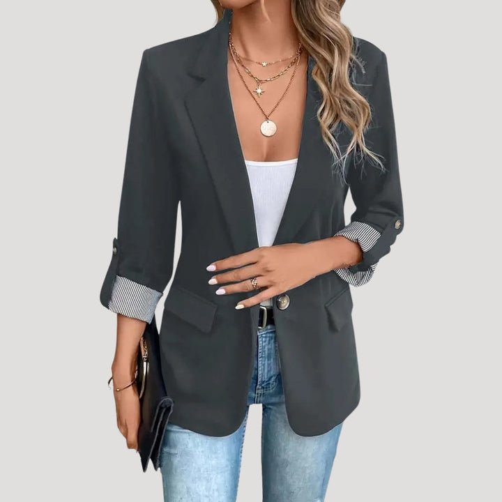 Damesblazer zij-aanzicht: elegante, getailleerde silhouette met opgerolde mouwen, essentieel voor damesmode.