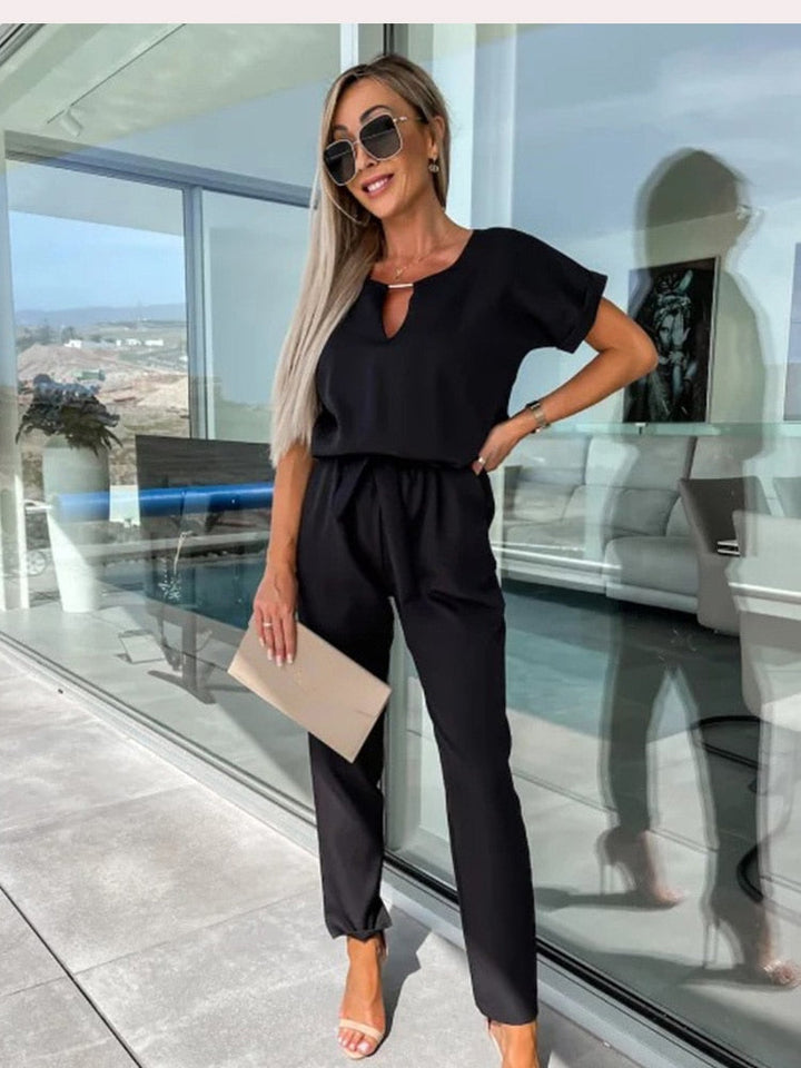 Elegante zwarte dames jumpsuit met korte mouw, V-hals en een subtiele strikceintuur, perfect voor avonden.