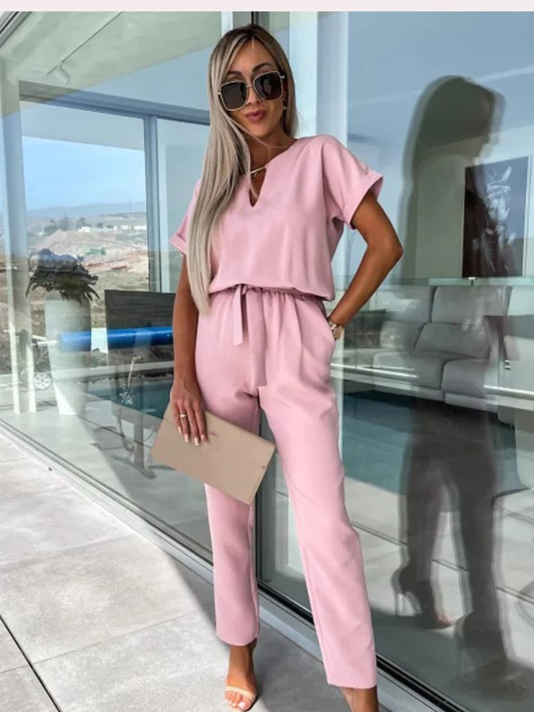 Stijlvolle dames jumpsuit in rozenrood, met een flatterende V-hals, korte mouw en bijpassende strikceintuur.