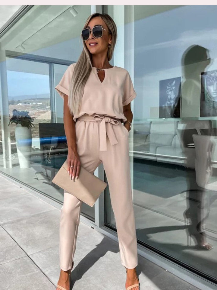 Zomerse kaki dames jumpsuit; comfortabel eendelig pak met korte mouw, V-hals en decoratieve strikceintuur.