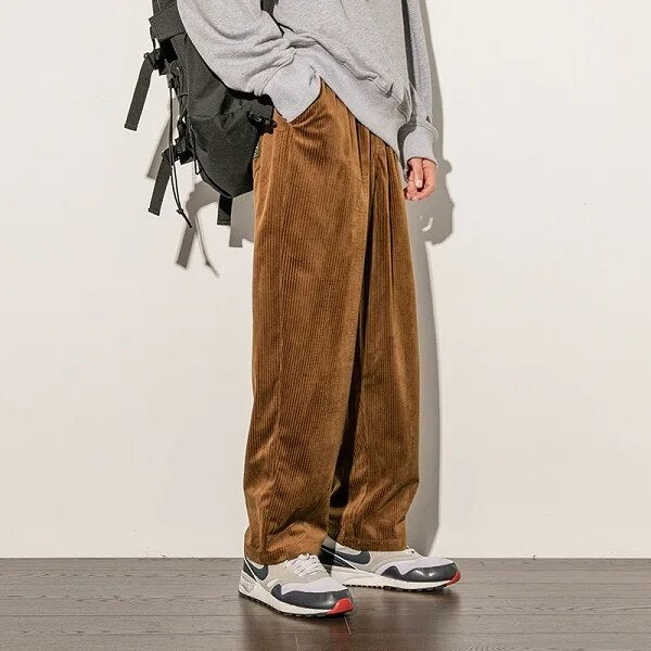 Man draagt bruine corduroy broek Finn met sneakers en rugzak
