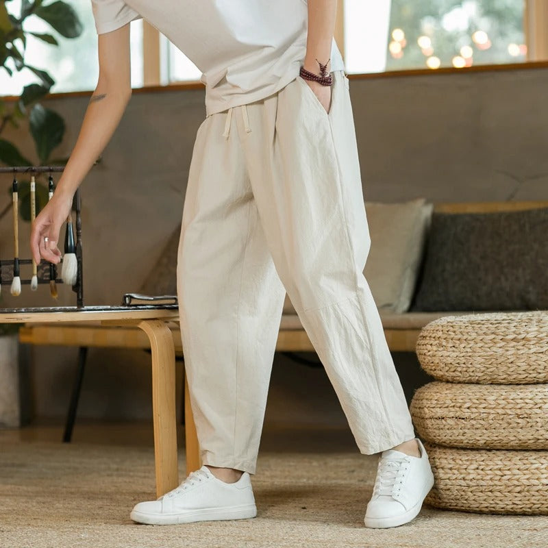 Man draagt een luchtige beige heren casual broek met witte sneakers