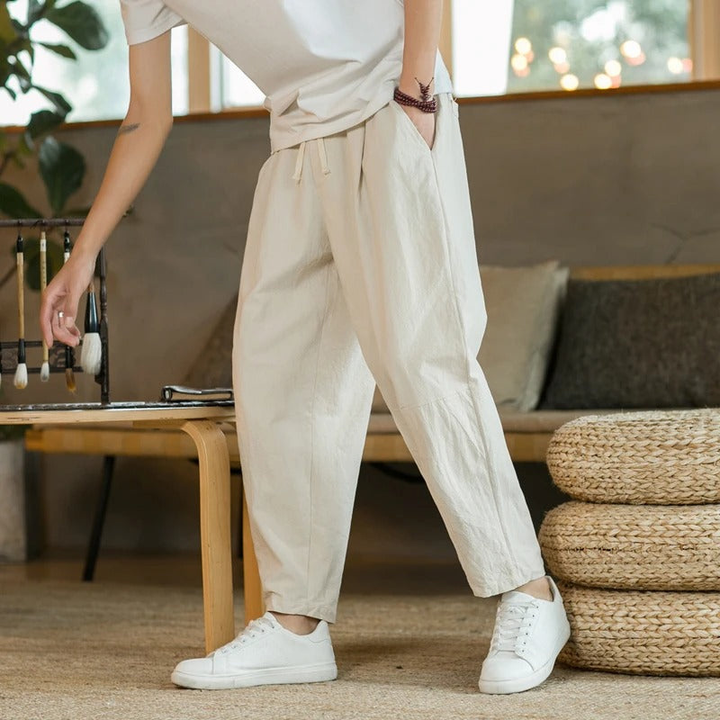 Man draagt een luchtige beige heren casual broek met witte sneakers