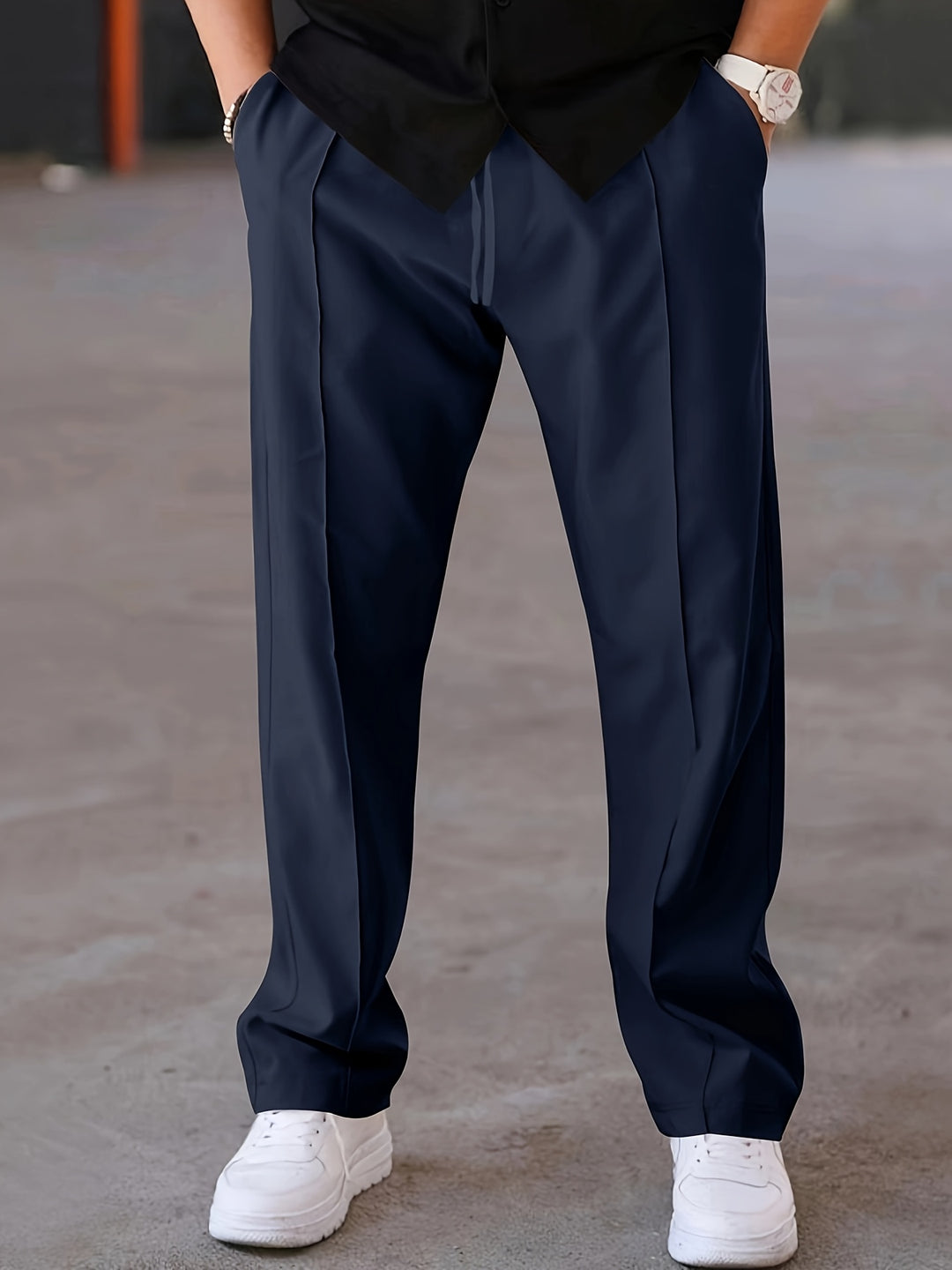 Donkergrijze herenbroek gecombineerd met sneakers voor een moderne uitstraling.