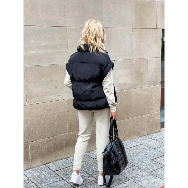 Achteraanzicht van dames in zwart puffer vest met zwarte handtas