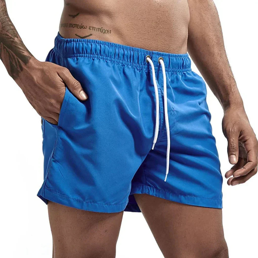 Actieve man in sneldrogende heren zwemshorts, spelend op het strand, ideaal voor watersport.