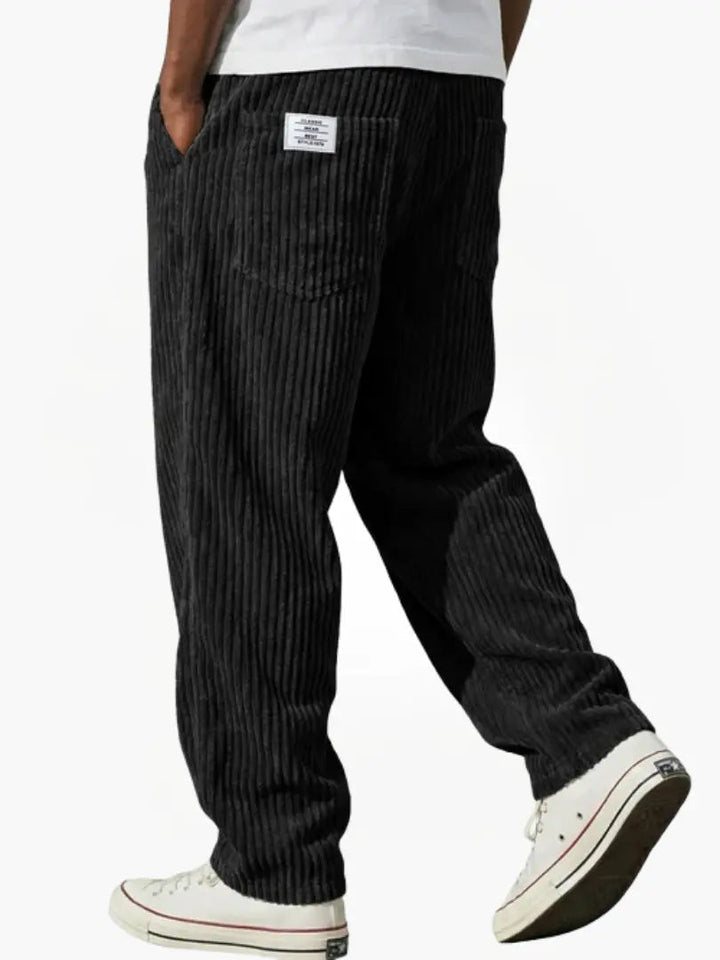 Praktische steekzakken op een stijlvolle heren ribbroek met comfortabele elastische tailleband en wijde pasvorm.