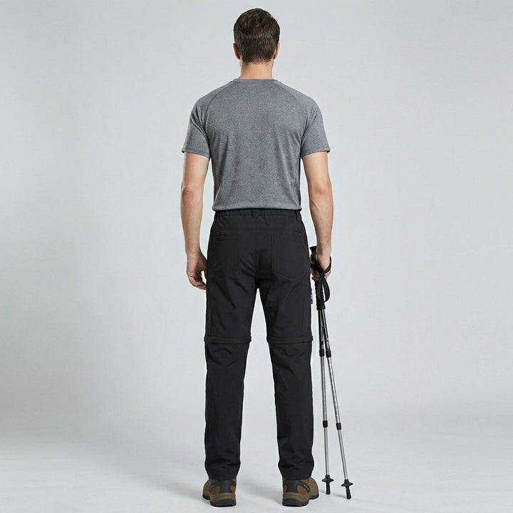Man van achteren met comfortabele outdoorbroek, toont flexibele pasvorm.