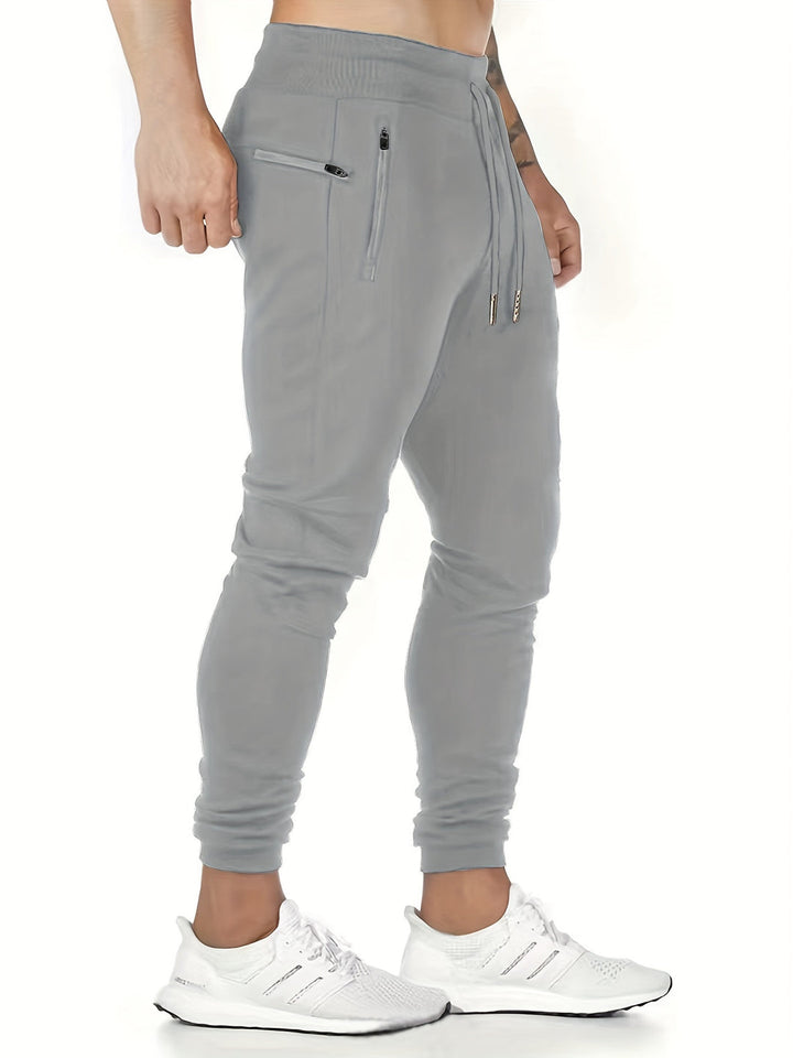 "Kastanjebruine heren joggingbroek van lichtgewicht polyester met ritszakken en trekkoord, ideaal voor lente en herfst."