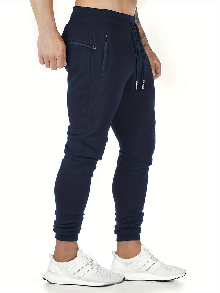 "Kastanjebruine heren joggingbroek van lichtgewicht polyester met ritszakken en trekkoord, ideaal voor lente en herfst."