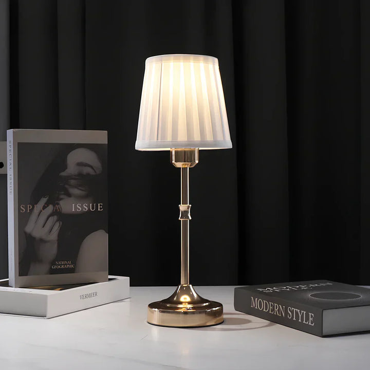 "Klassieke tafellamp met metalen frame en stoffen kap in een interieur, draadloos met drie lichtstanden."