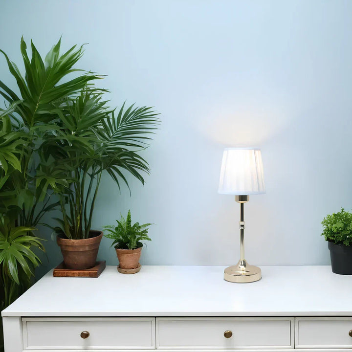 "Klassieke tafellamp met metalen frame en stoffen kap in een interieur, draadloos met drie lichtstanden."