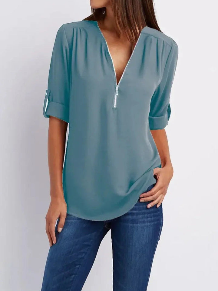 "Luchtige Emilia zomerblouse met v-hals en halve rits in zachte stof, ideaal voor casual zomeroutfits."